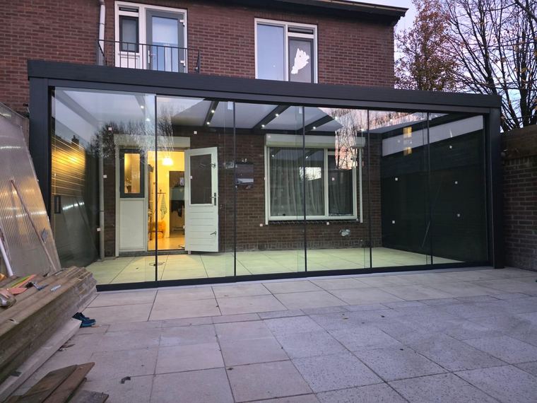 Veranda met glazen schuifwanden bij avondlicht
